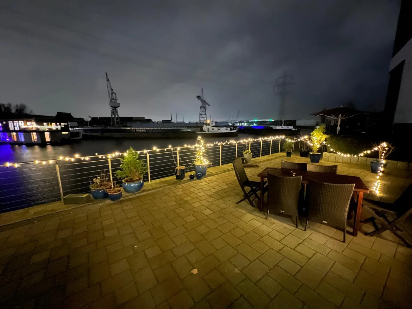 Terrasse am Abend mit Lichterketten und Blick auf die Hafenkräne